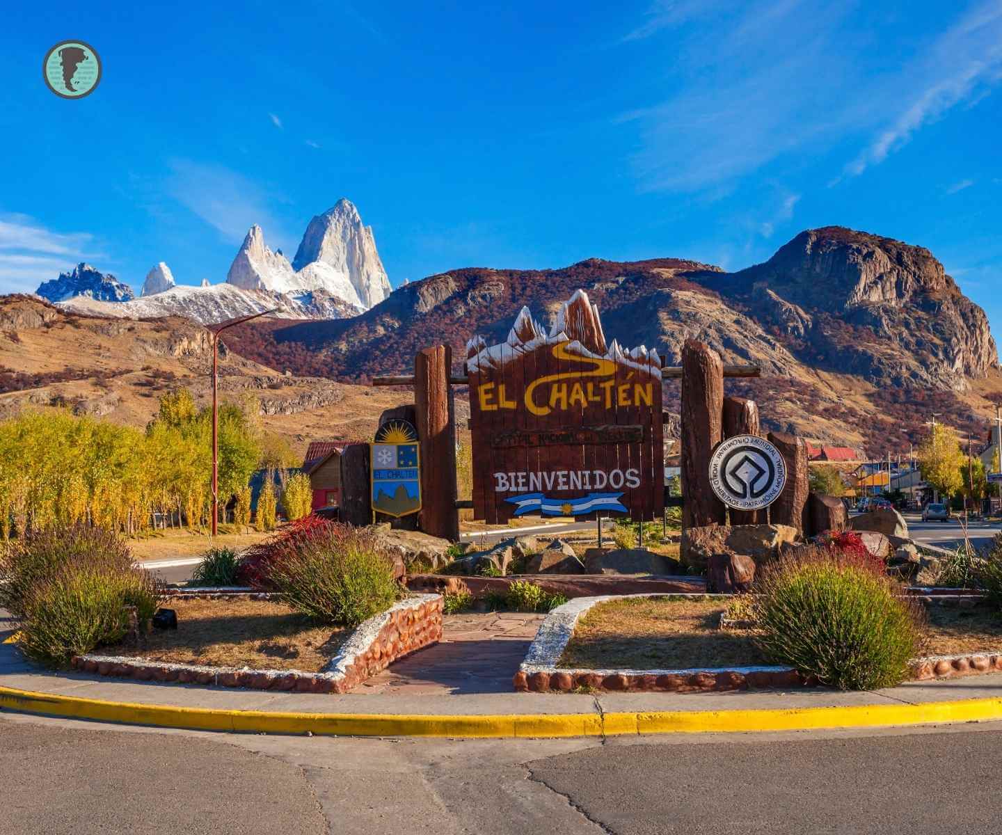 Cartel de bienvenida a El Chaltén con el Fitz Roy al fondo en un día soleado